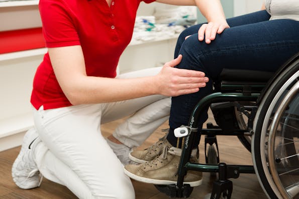 Therapeutin behandelt Patientin im Rollstuhl